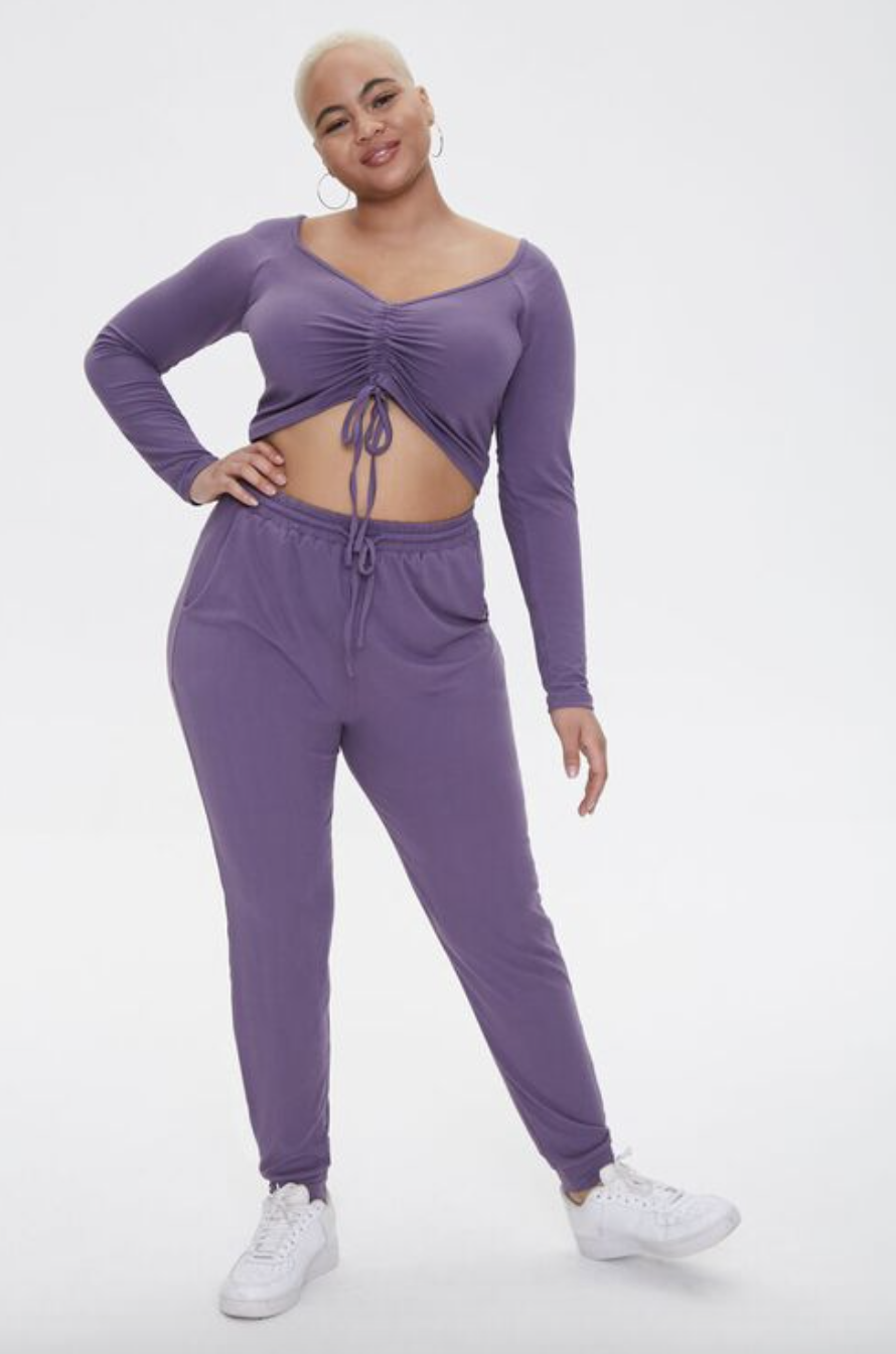 model in purple ruched crop top and sweatpants set and sneakers