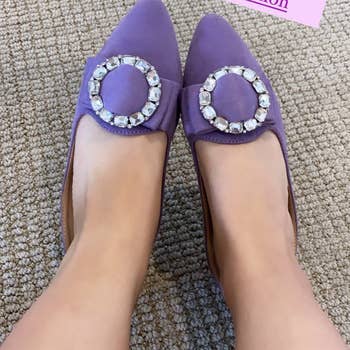 Reviewer wearing the lavender pointed toe slides with a rhinestone buckle with text