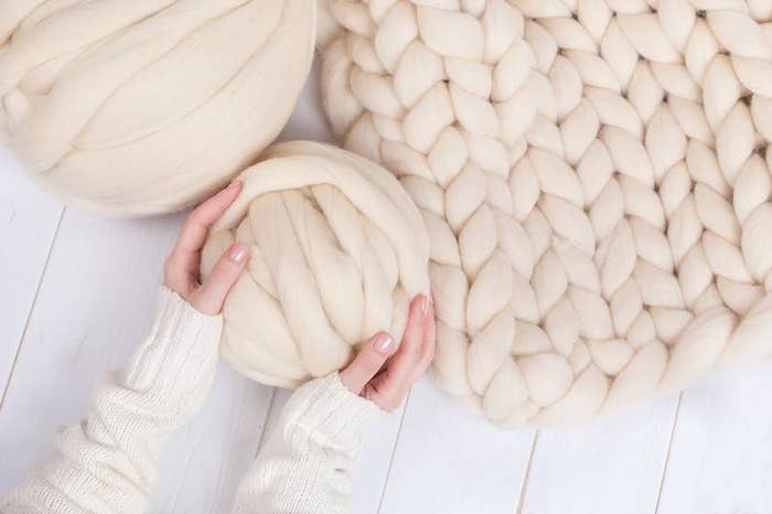 A person holding a ball of chunky yarn
