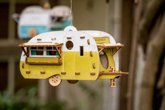 A tiny camper birdhouse handing from wire 