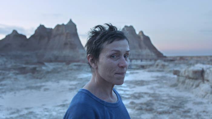 Frances McDormand as Fern in Nomadland standing in front of rock pinnacles at sunset