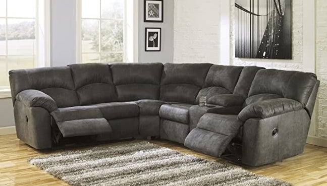 A dark gray L-shaped sectional with both the end seats in a reclining position and two cup holders by the right-most seat
