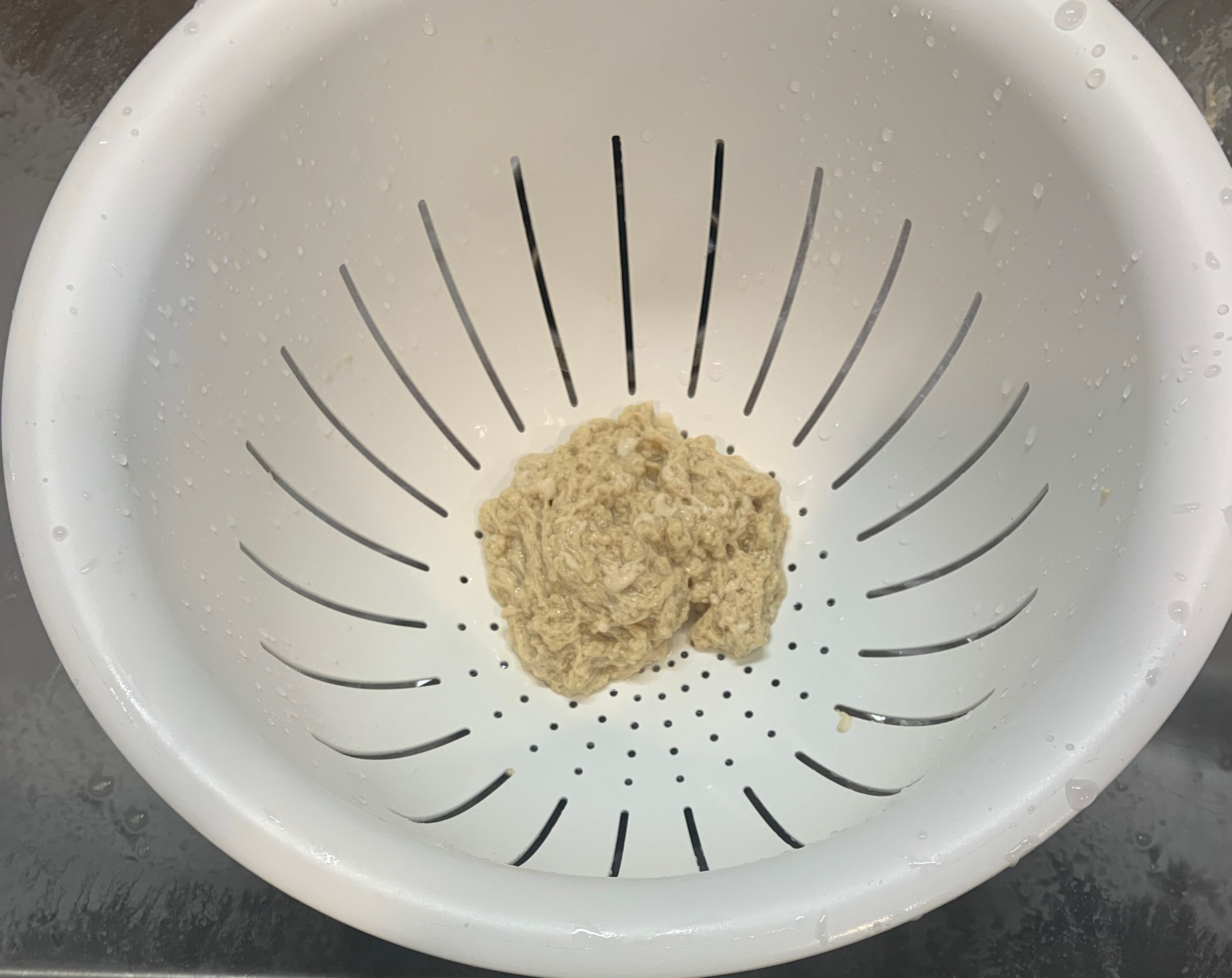 snot-looking dough in a colander in the sink