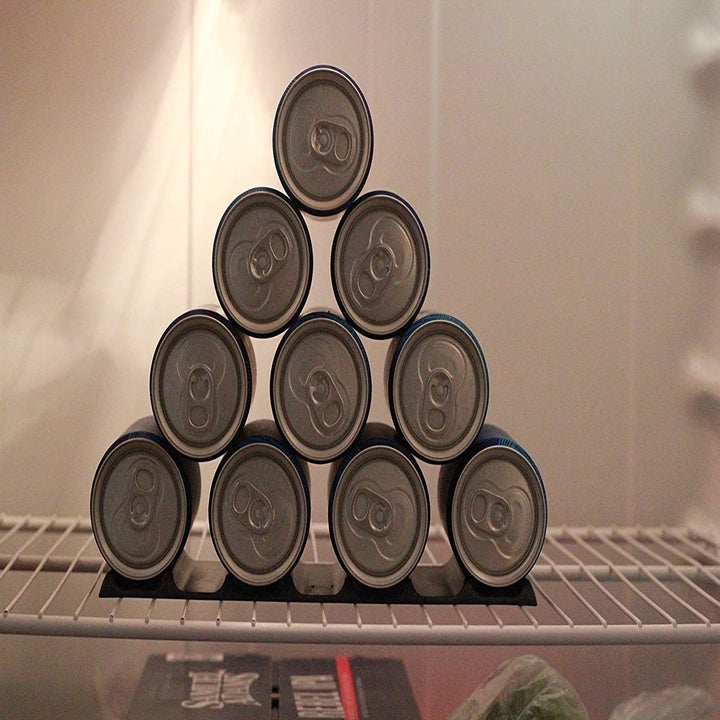 Pyramid of cans on top of rubber man inside fridge