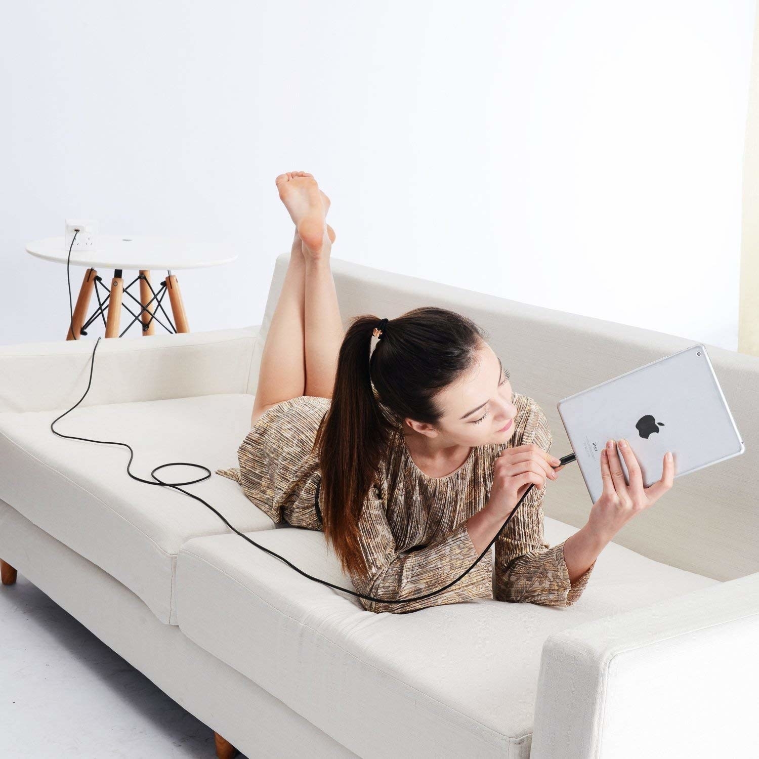 Model on couch plugging in 10-foot charger corn into iPad