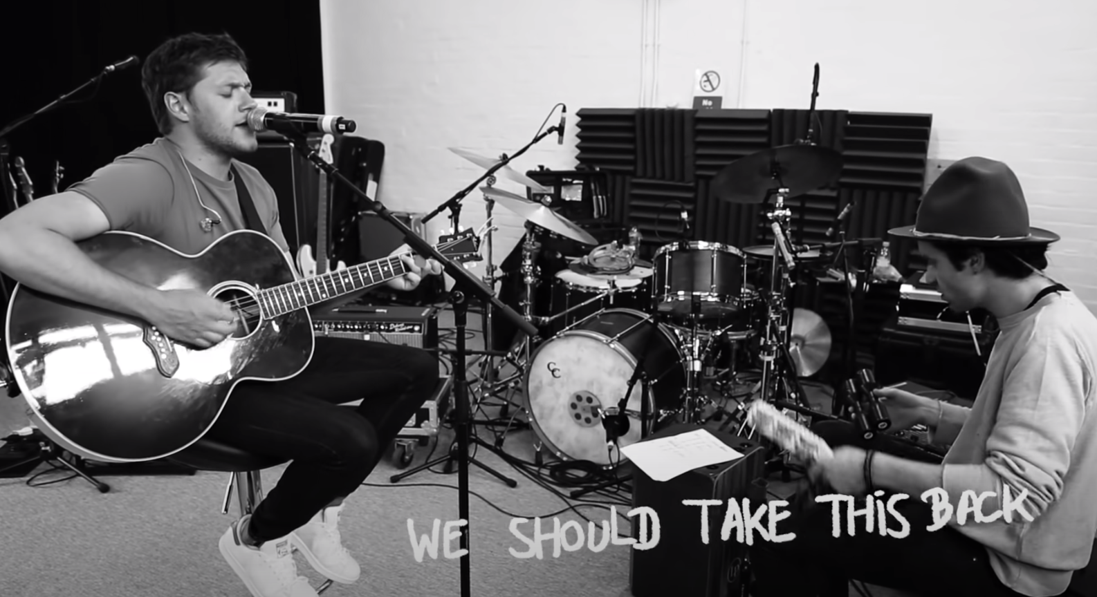 Black-and-white photograph of Niall singing and playing guitar