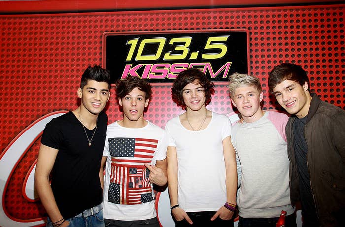 The members of One Direction smiling at the camera above a 103.5 KissFM banner