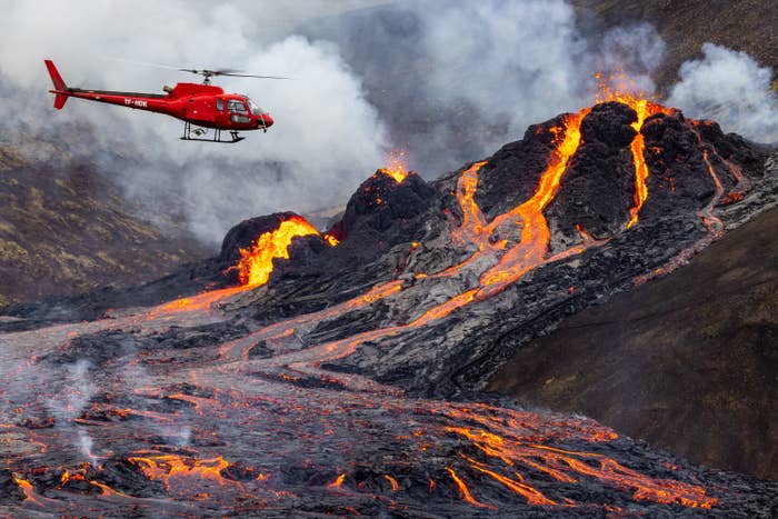 Helicopter flies over volcano with lava