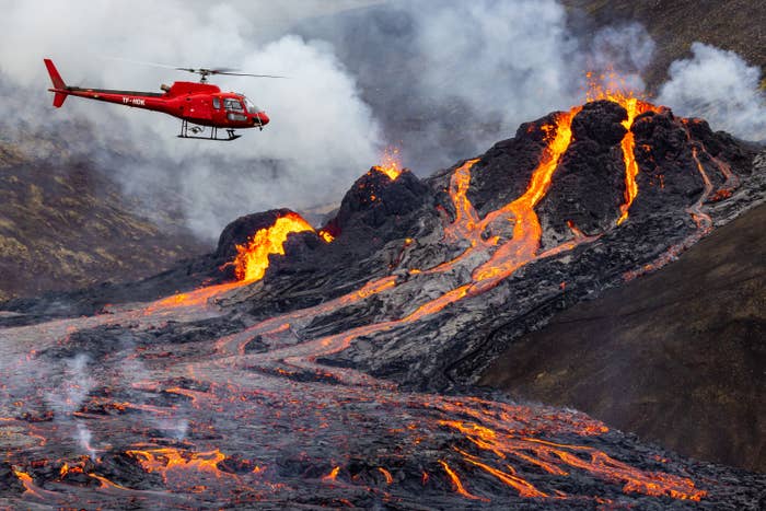 Helicopter flies over volcano with lava 