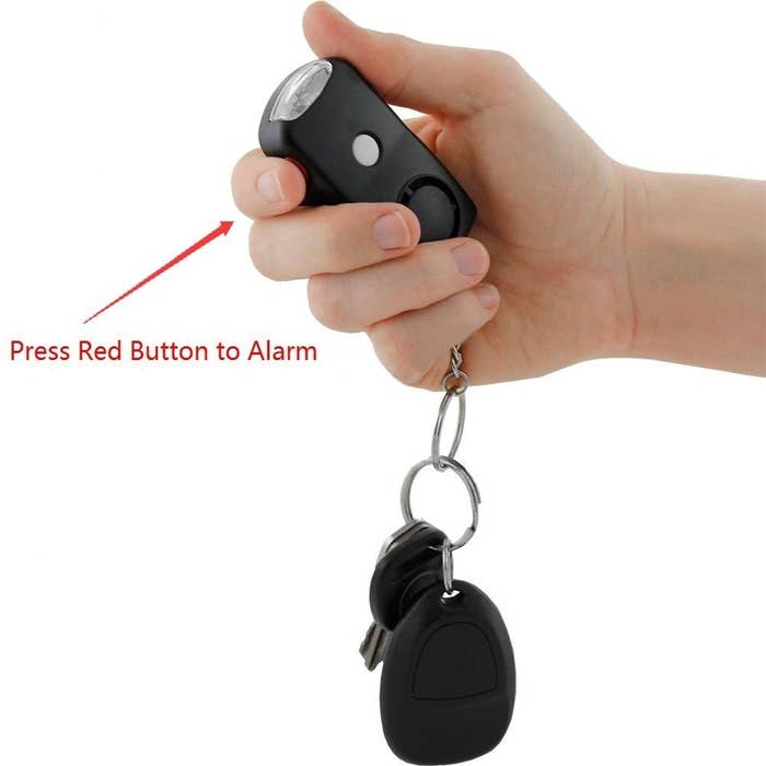 A person holding the keychain, with text pointing to it that says “Press red button to alarm”.