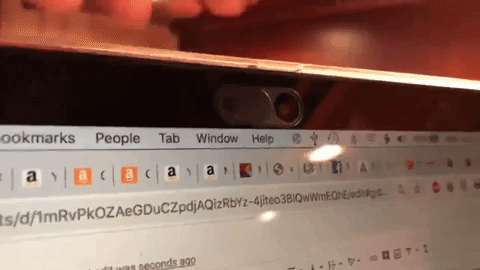 Reviewer closing webcam cover on laptop