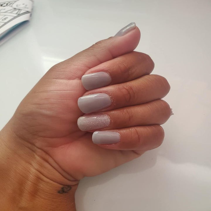 Reviewer with periwinkle nails and glittery white accent nail
