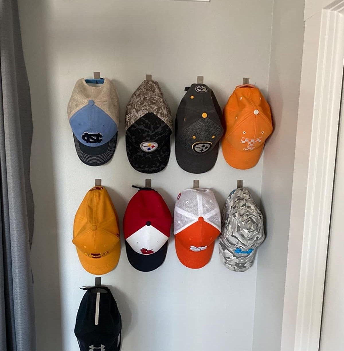 reviewer showing their nine baseball caps hanging neatly on the wall hooks 