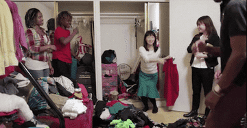 Marie Kondo with a large group of people cheerfully cleaning out a closet