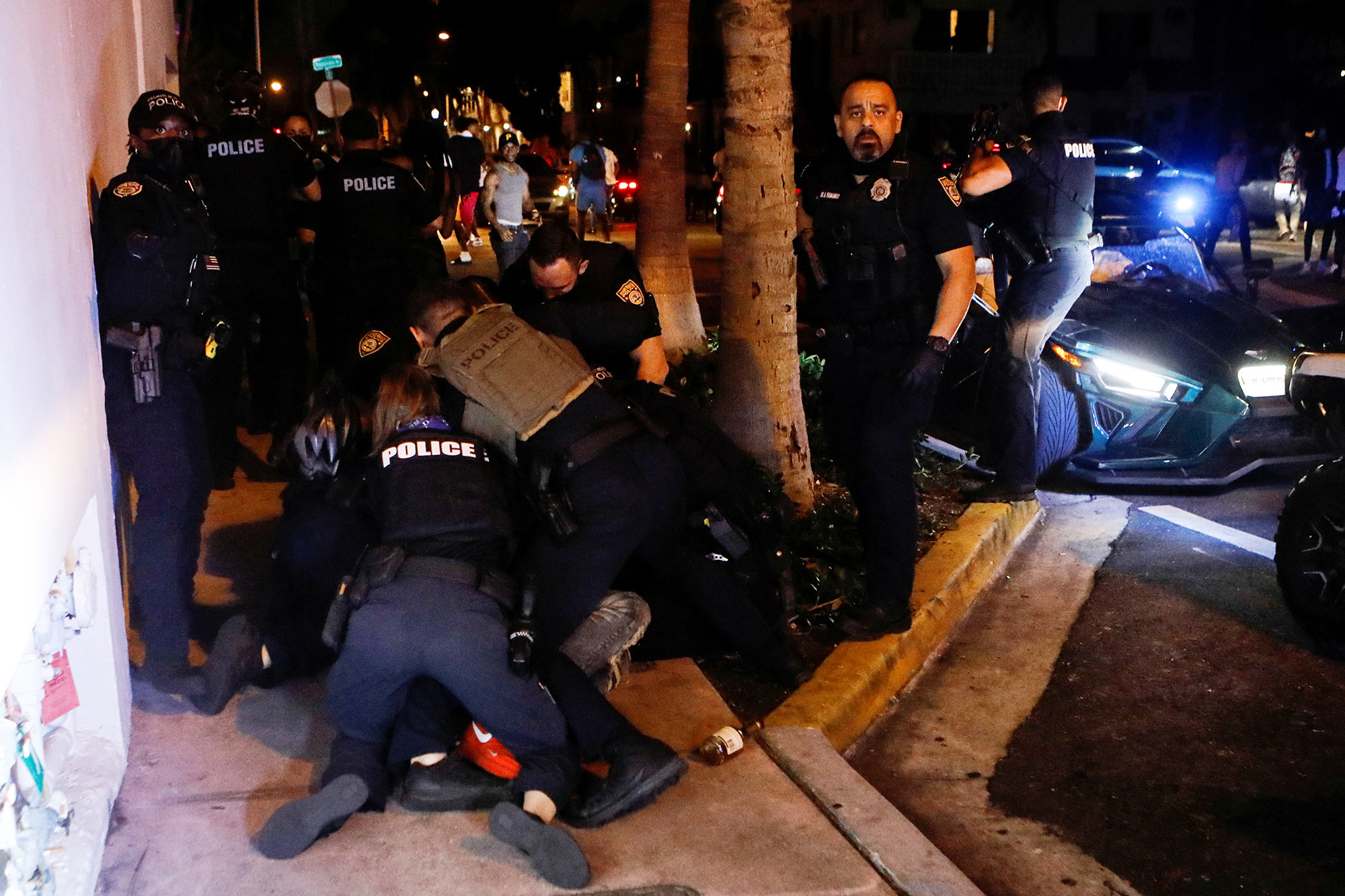 At least 6 police officers tackle a person on the ground, unseen