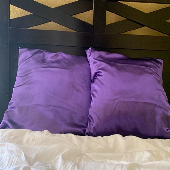 a reviewer photo of two pillows with purple satin pillowcases