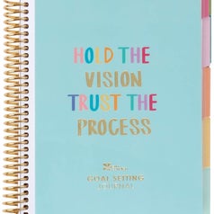 a blue coiled planner that says "Hold the vision, trust the process" with multicolor tabs on the right 