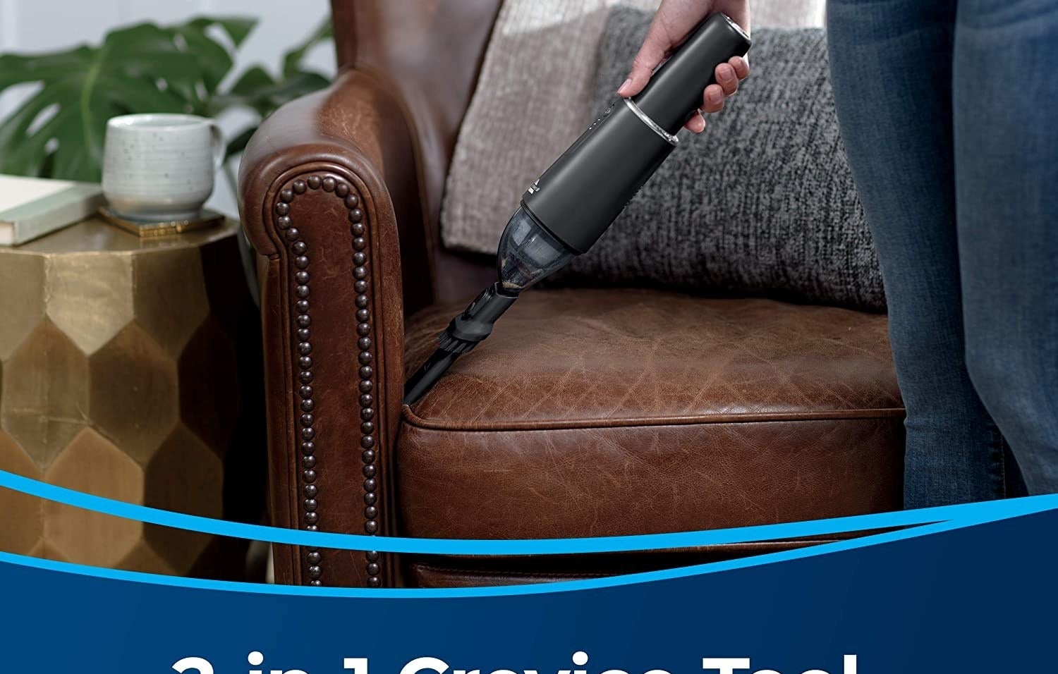 Person reaching the corners of their couch cushions with the small vacuum 
