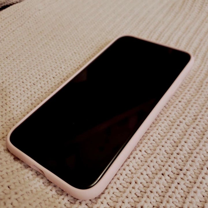 a reviewer's phone showing a light pink bumper around it