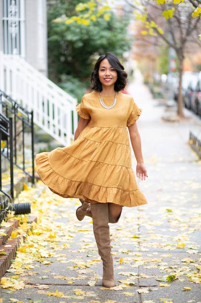 a reviewer wearing the knee-length dress in a mustard yellow