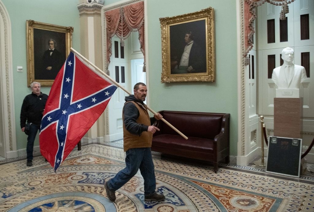 one of Trump&#x27;s insurrectionists carrying a confederate flag through the Capitol
