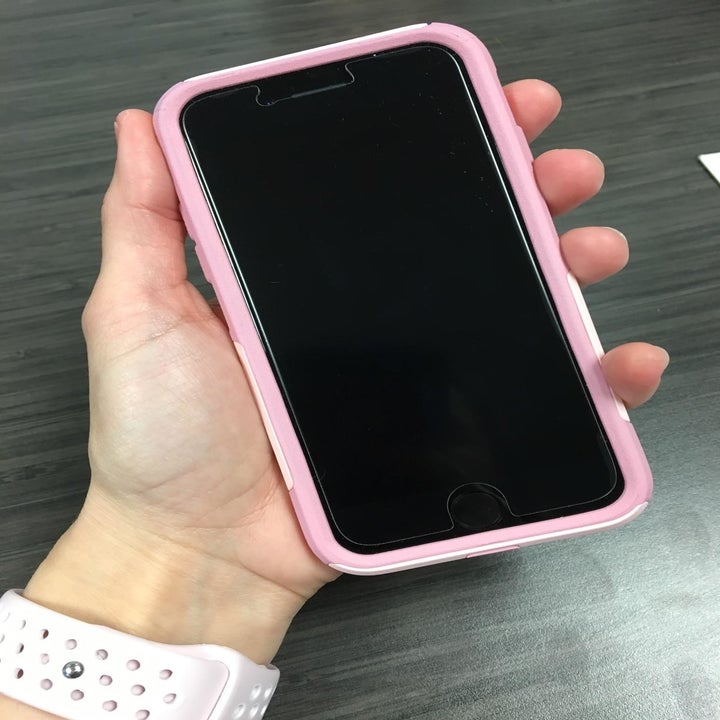 a reviewer with a phone in their hand with a pink bumper around it