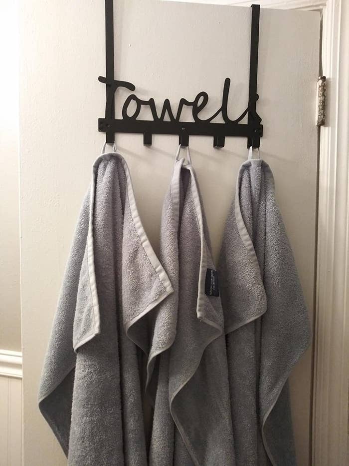 Three towels hung on a hook that reads &#x27;towel&#x27;