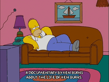Homer Simpson lounging on a couch watching a meta documentary about Ken Burns