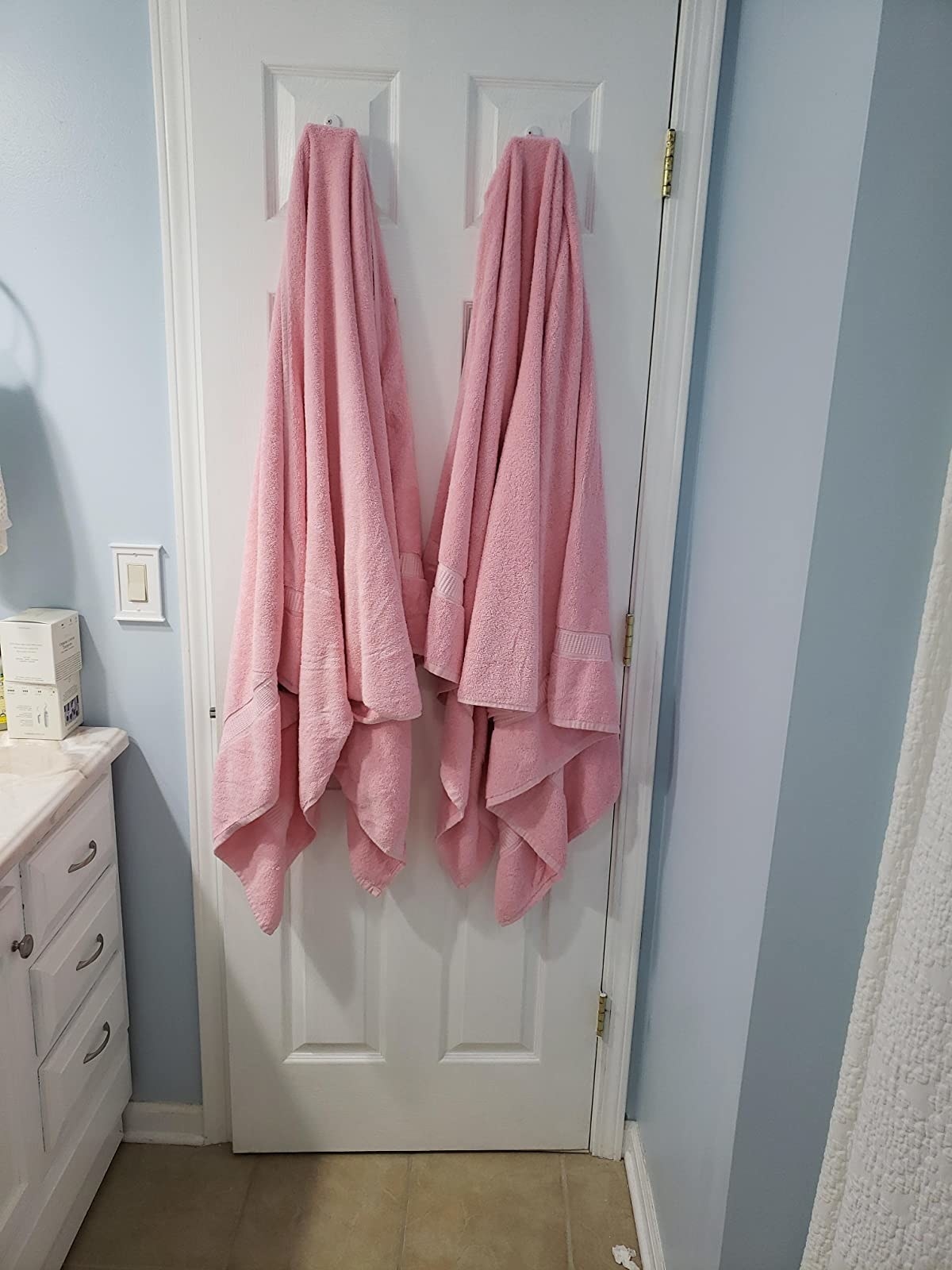 Two large pink towels on a door