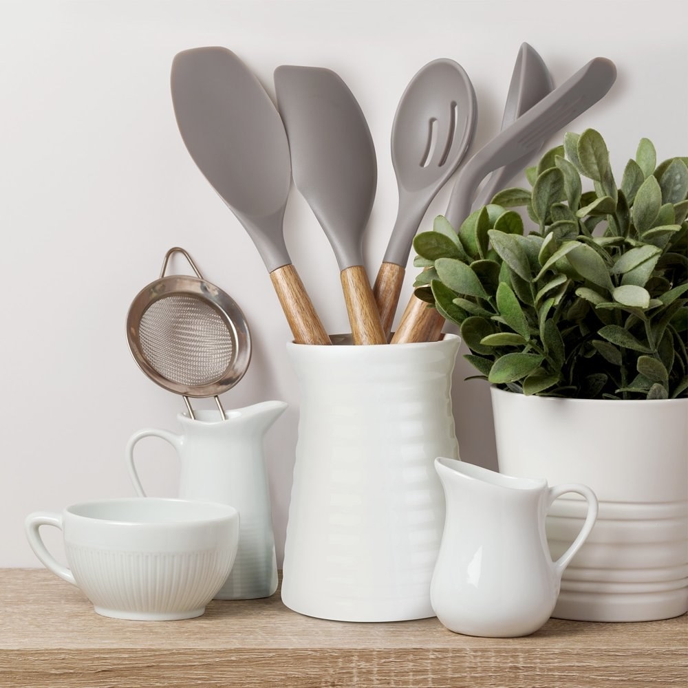 gray utensil set in a white container on a shelf 