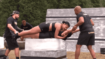 Cast members laying on top of one another as two other cast members rub their bodies back and forth on a giant block of ice