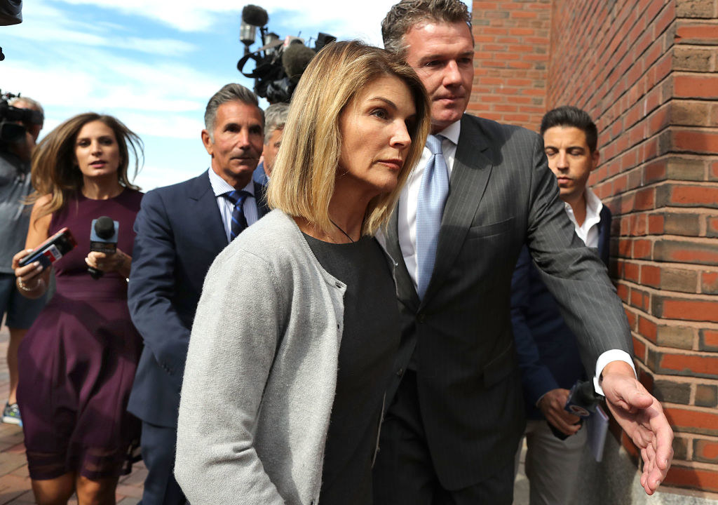 Lori Loughlin and her husband Mossimo Giannulli, behind her at left, leave the John Joseph Moakley United States Courthouse in Boston