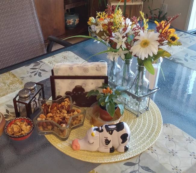 reviewer image of the wrapables cow mini tabletop vacuum in the center of a dining table along with bowls of snacks, napkins, and a salt and pepper shaker
