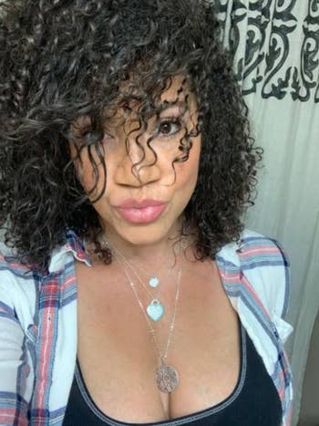 A reviewer showing off her tight curls after using the style milk