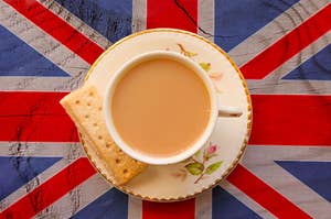 A cup of tea and a biscuit sitting on top of a british flag