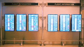 People passing by flight information screens.