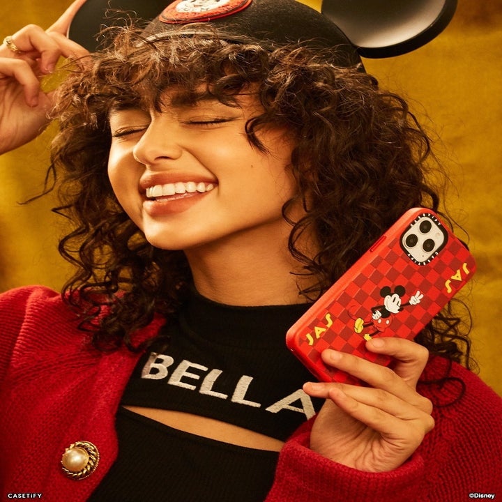 a model holding a red checkered phone case with mickey on it 