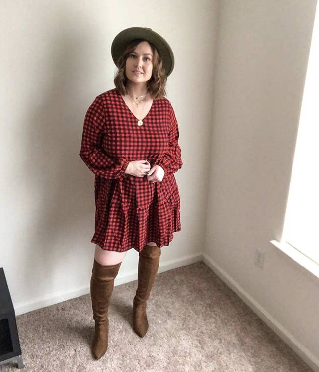 Reviewer photo of a person wearing a red and black checkered dress with brown boots and a black hat