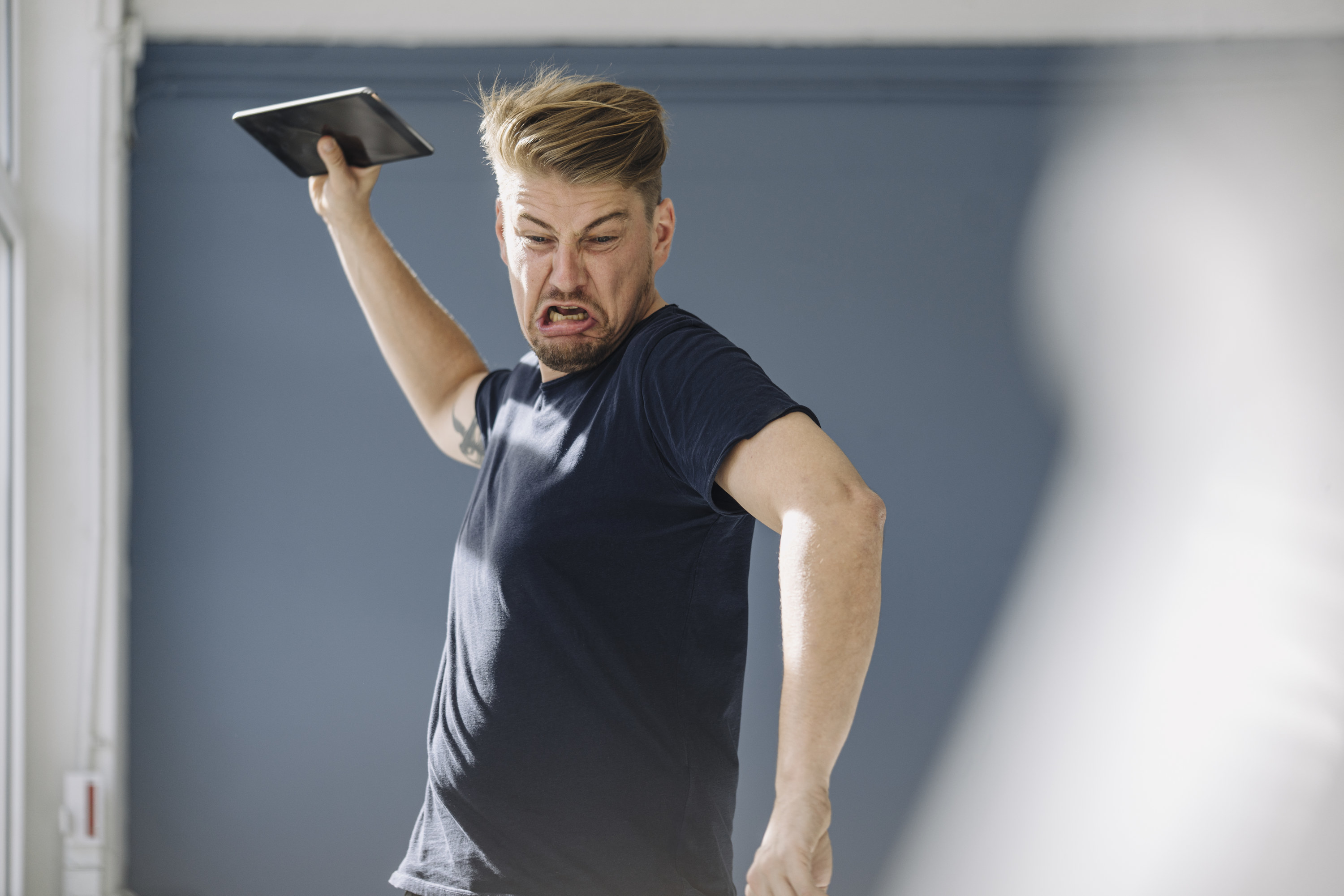 Angry man throwing his tablet on the floor