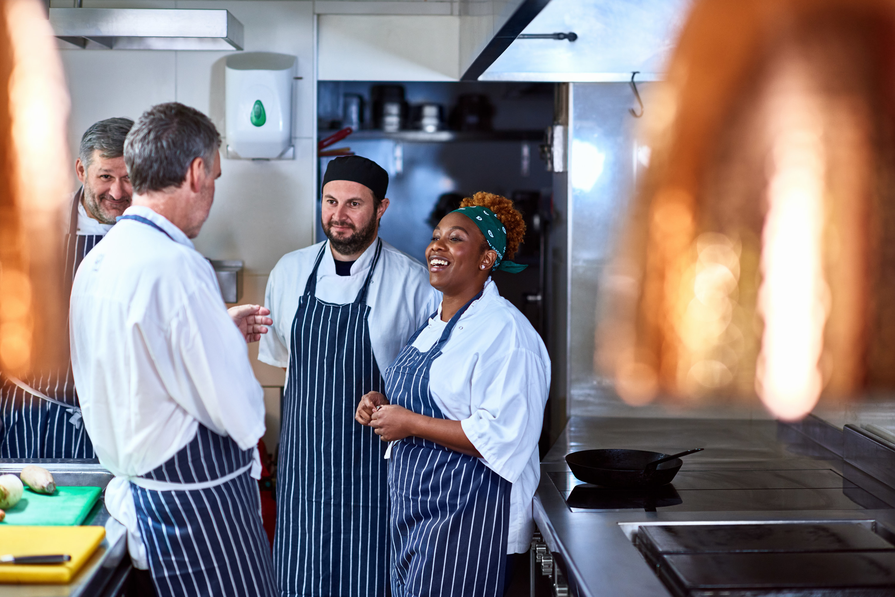 Four restaurant colleagues talking in a friendly manner in the kitchen