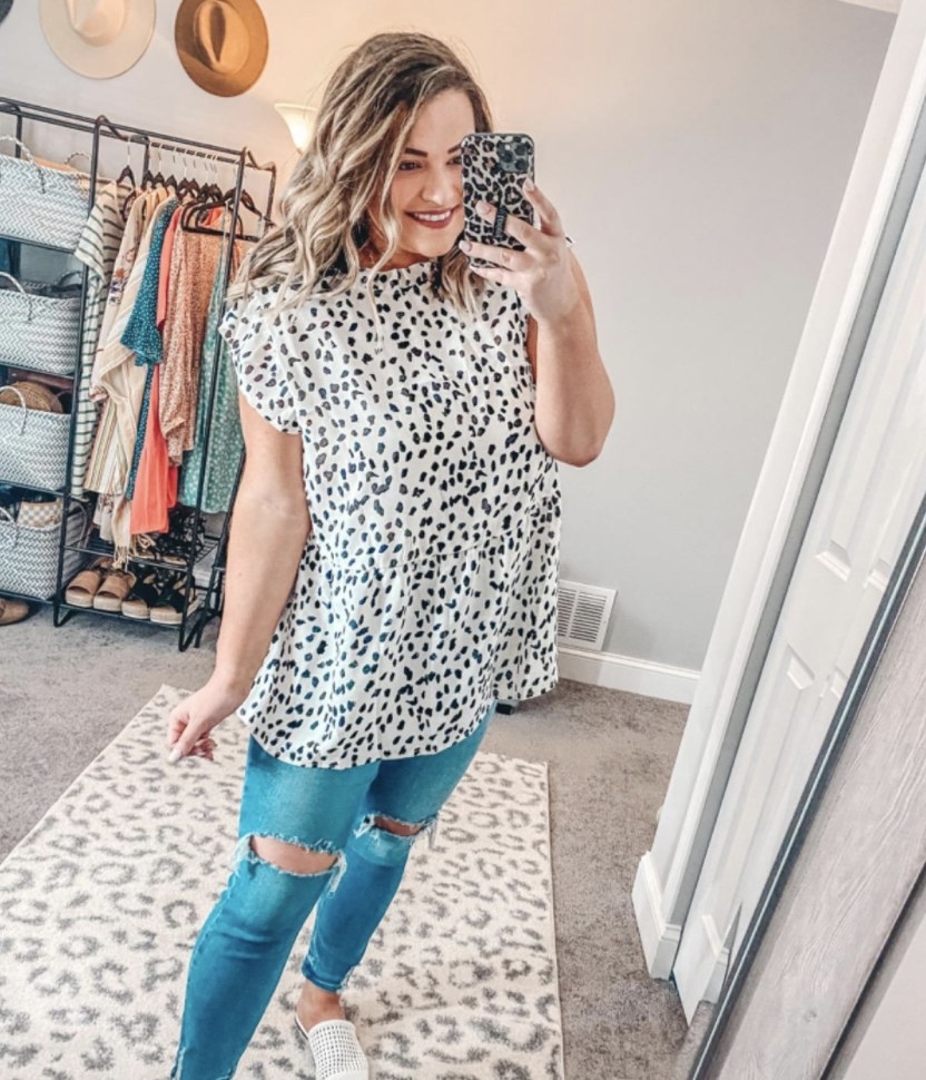 Reviewer photo of a person wearing a white and black dotted tunic and denim jeans