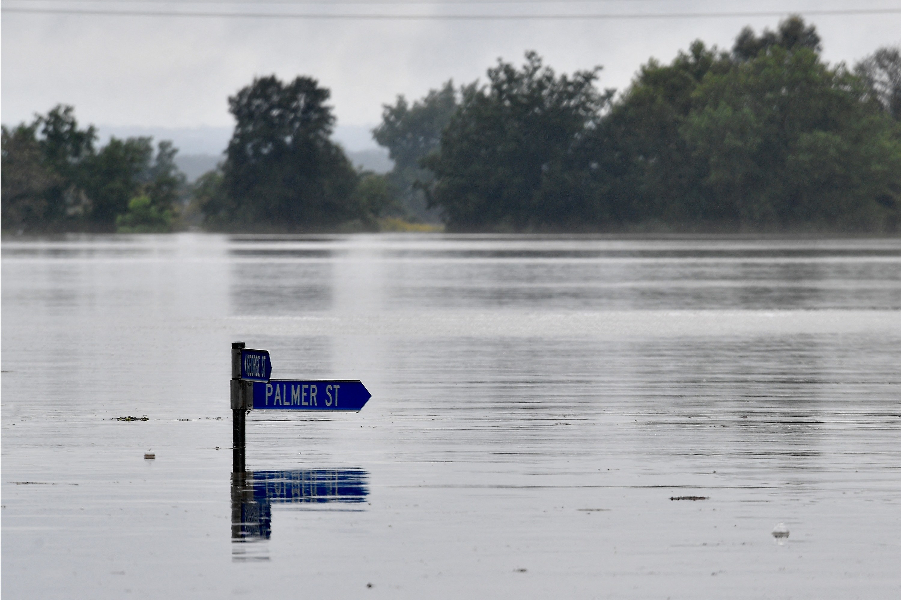 A street sign that reads &quot;Palmer Street&quot; is just visible above a flooded residential area. 