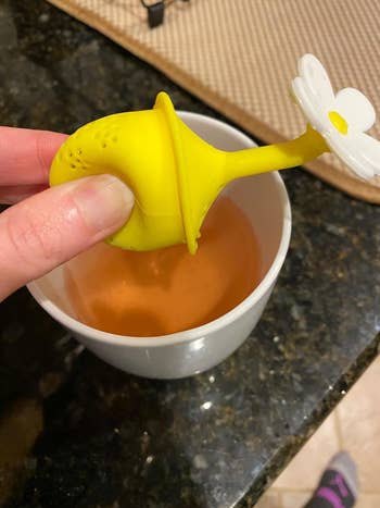 image of reviewer squeezing a Sfizzio daisy tea infuser over a full mug of tea