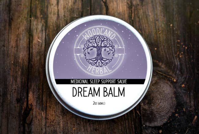 a tin of the dream balm in silver, white, and purple packaging