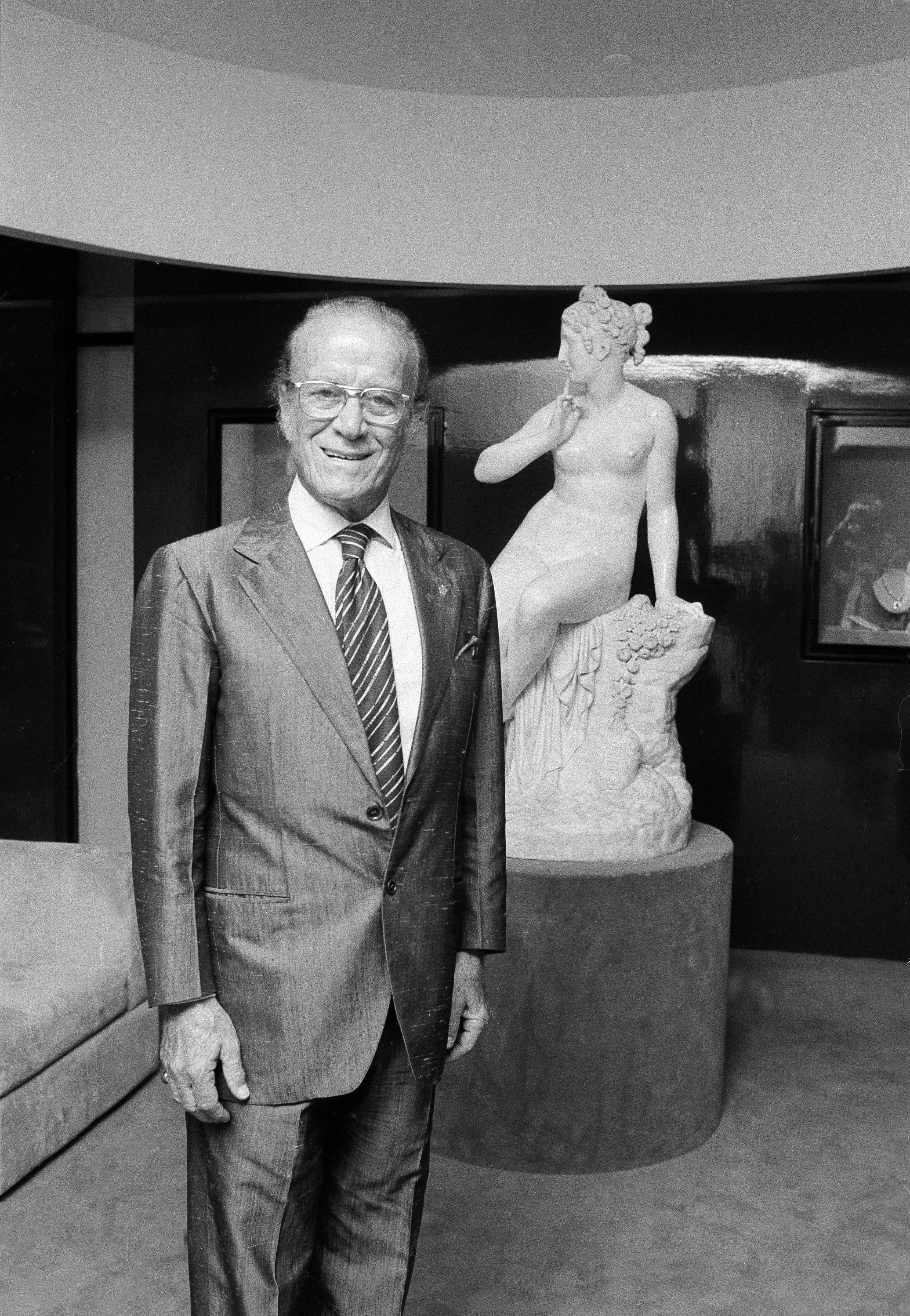 Aldo Gucci standing in front a statue