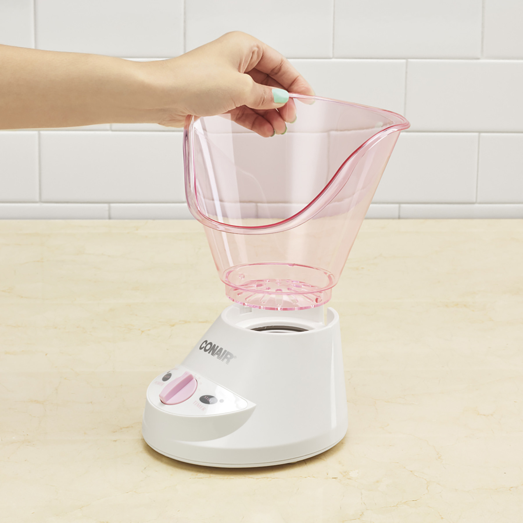 A pink and white volcano shaped facial steamer on a counter
