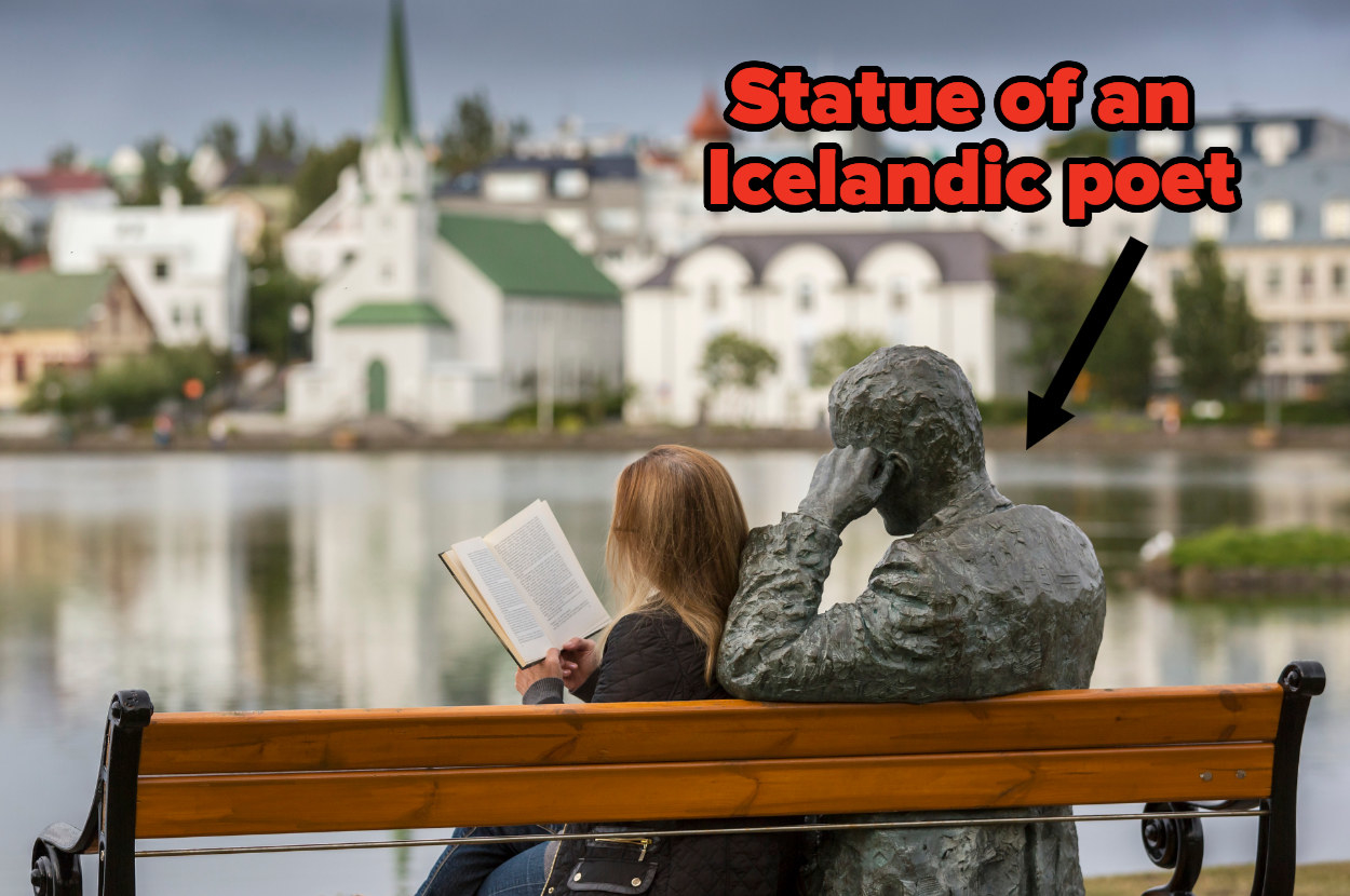 A woman sits on a bench overlooking Reykjavik next to a statue of an Icelandic poet
