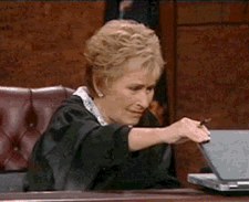 Judge Judy grimaces as she peaks at a laptop screen, then closes it on Judge Judy