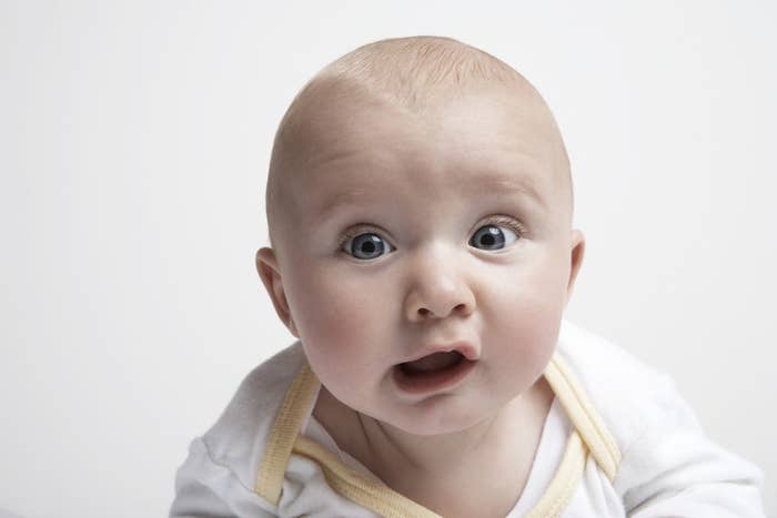A white baby with blue eyes looks into the camera with a confused face
