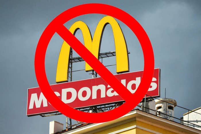 A McDonald&#x27;s sign against a gray sky with a superimposed red &quot;no&quot; symbol over it
